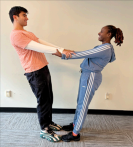 two people standing toe to toe with clasped hands and leaning backward